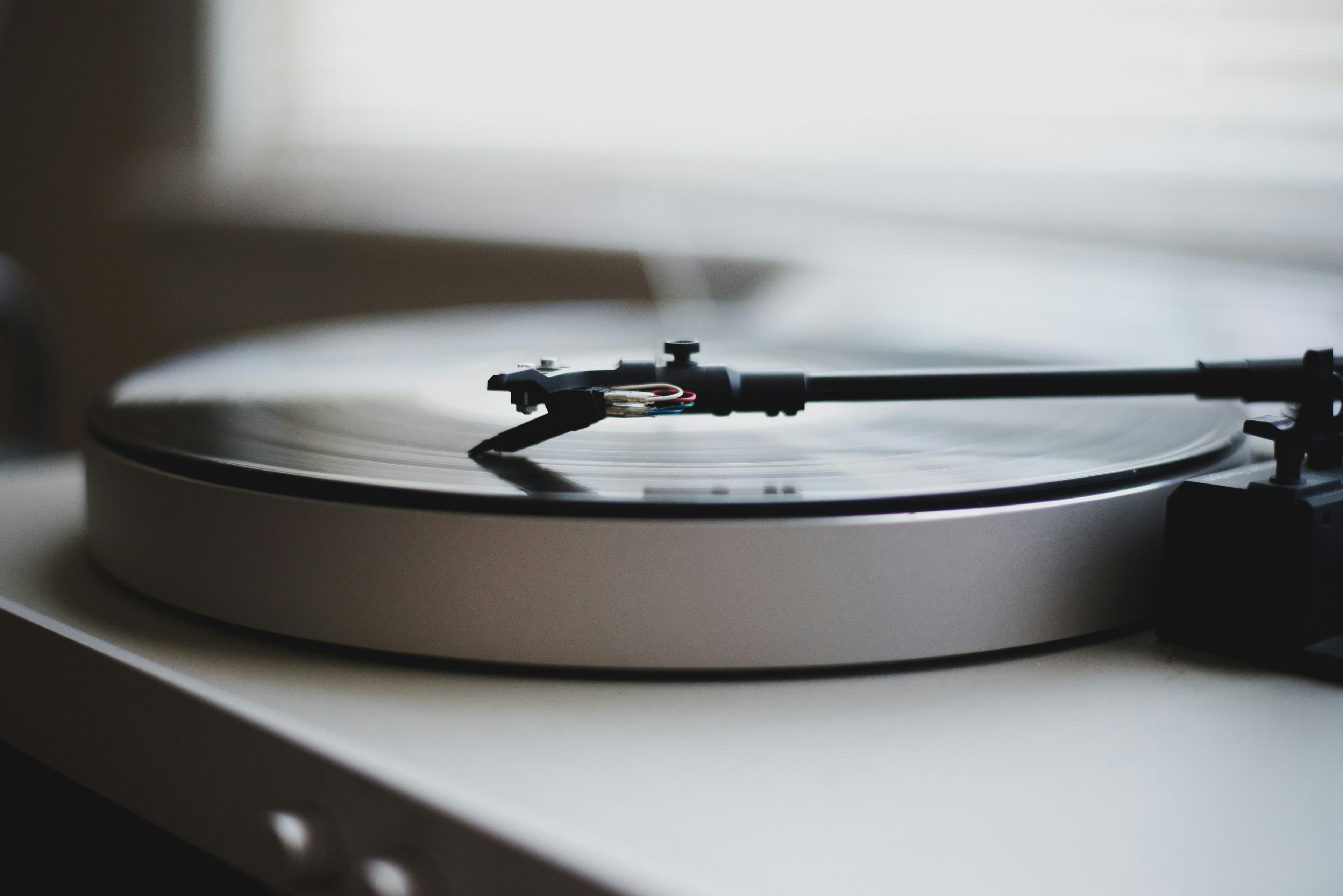 A close view of the headshell at the tip of the tonearm, with the cartridge mounted beneath it and the four colored headshell wires visible.