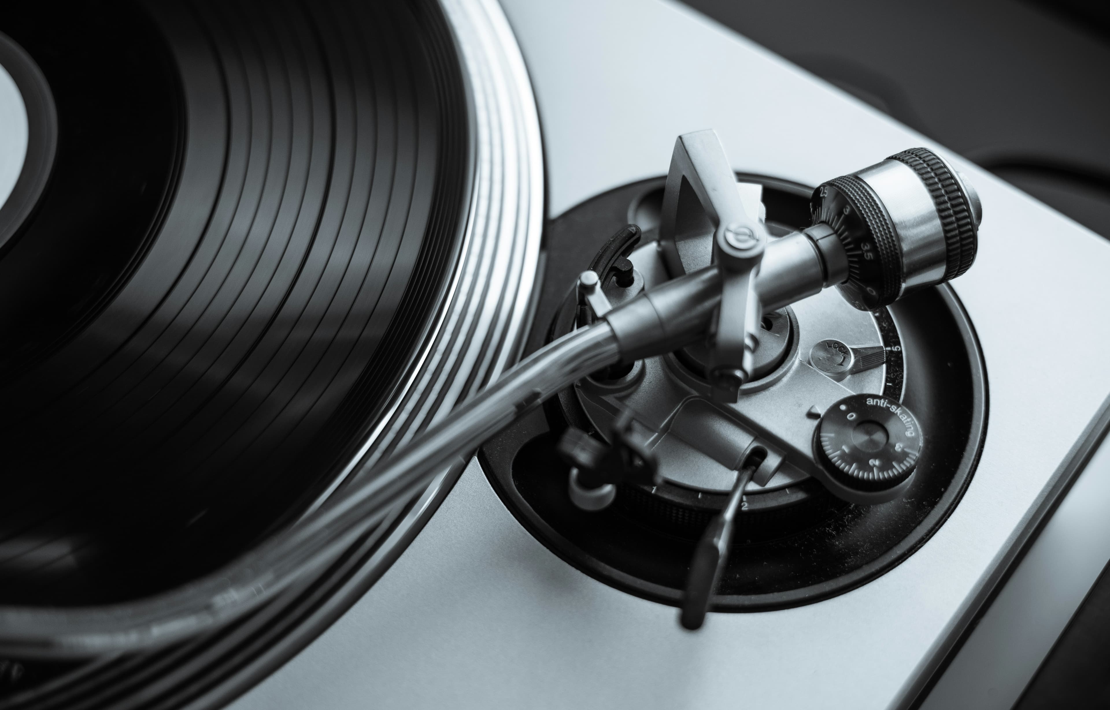 An overhead close-up of the tonearm base, with the knurled counterweight and its numbered tracking-force ring at the back and the anti-skate dial beside the pivot.