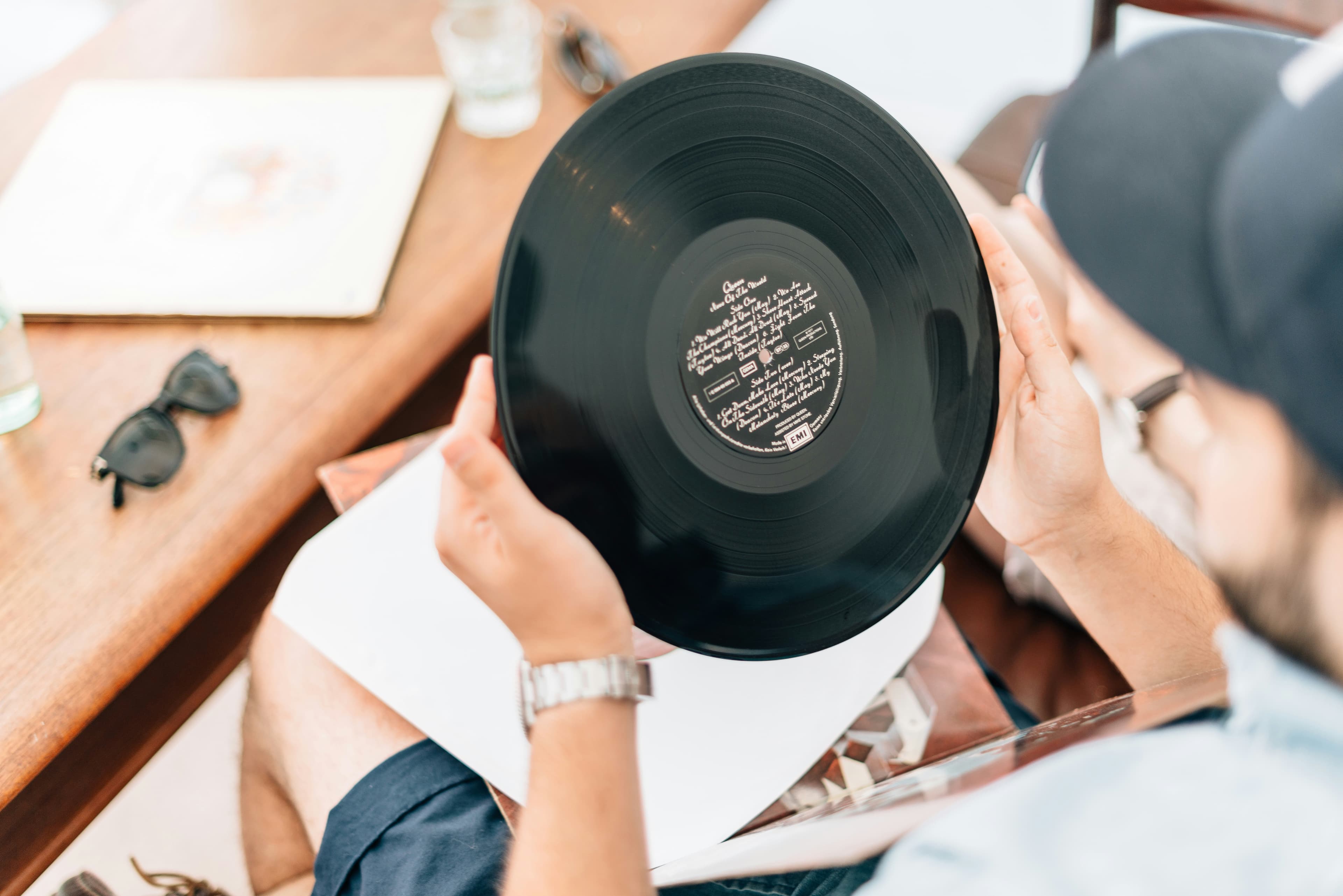 Holding a record by its edge and label, fingers kept clear of the grooves.
